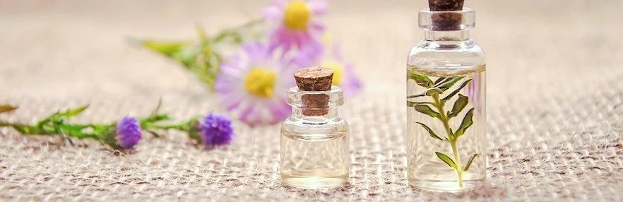 ätherisches Öl in Glasfläschchen mit Blumen