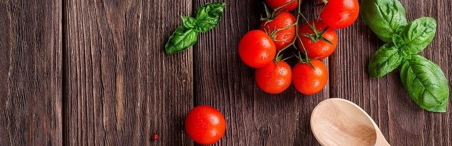 Arbeitsfläche mit Kochlöffel und Tomaten